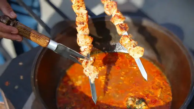 Суп с мясом, жаренными овощами и яйцами в казане на костре