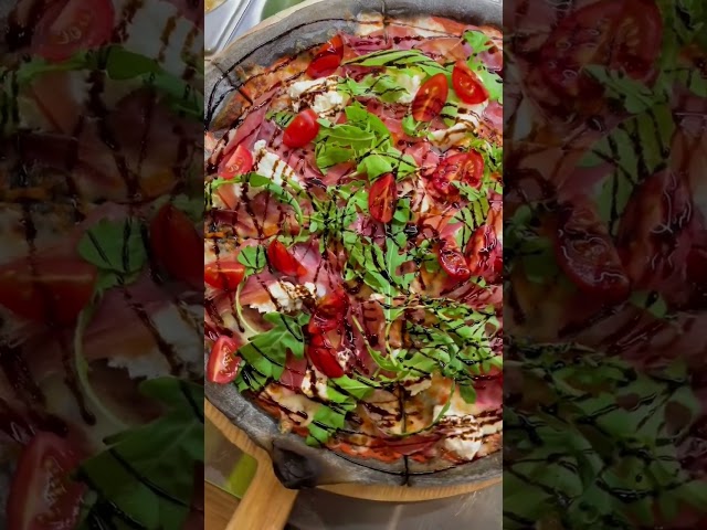 Пицца с чернилами каракатицы, страчателлой, ветчинной, рукколой, томатами и бальзамическим соусом
